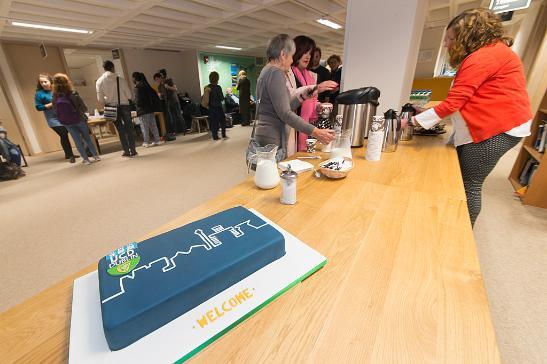 A lovely blue cake with students in the background enjoying coffee