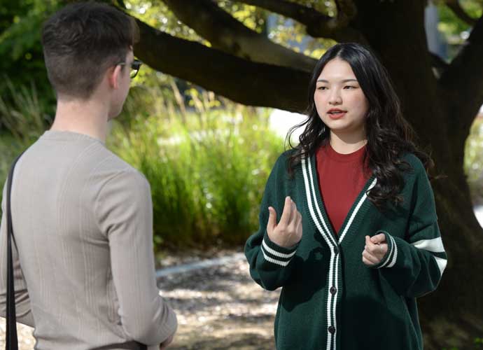 Two students talking under a tree