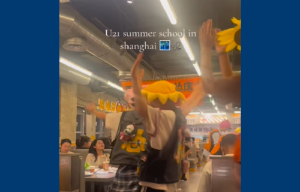 Person with orange hat and arms raised in restaurant dancing