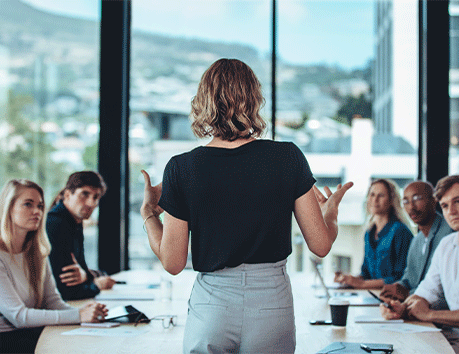 woman in boardroom meeting leading discussion with back faced towards camera